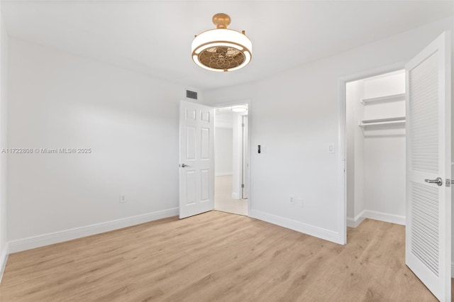 unfurnished bedroom with a walk in closet, light hardwood / wood-style floors, and a closet