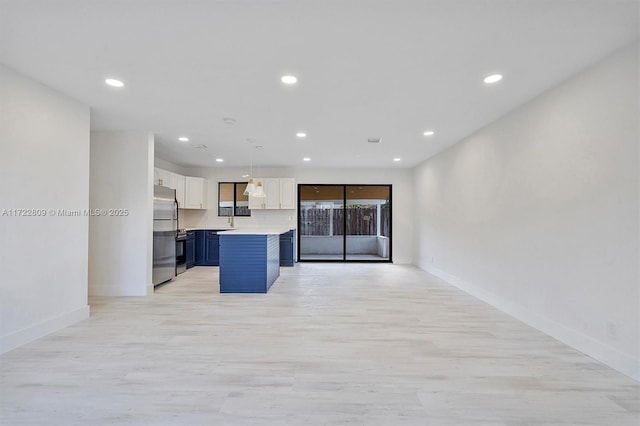 kitchen featuring pendant lighting, a center island, blue cabinets, stainless steel fridge, and white cabinetry