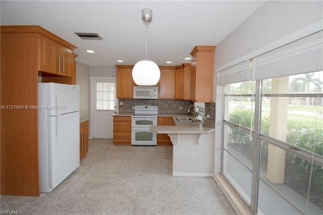 kitchen featuring kitchen peninsula, pendant lighting, white appliances, decorative backsplash, and a breakfast bar