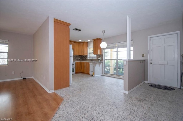 kitchen with kitchen peninsula, tasteful backsplash, sink, decorative light fixtures, and white fridge