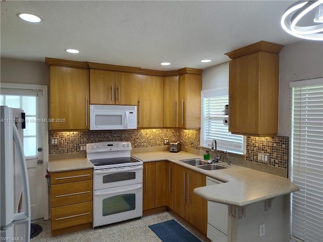 kitchen with pendant lighting, backsplash, white appliances, and sink