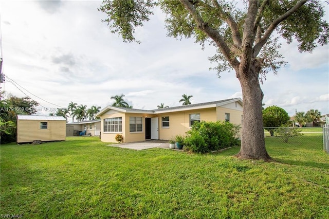 back of house with a lawn, a patio, and a storage shed