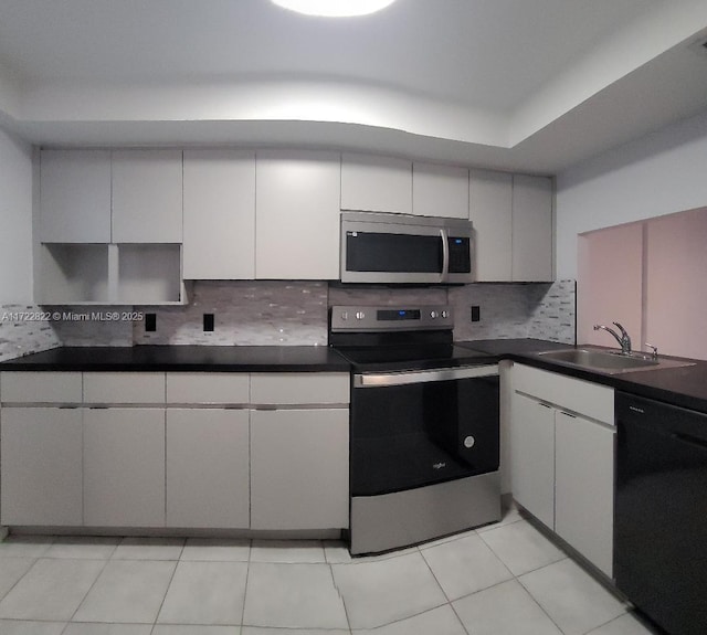 kitchen featuring sink, stainless steel appliances, light tile patterned floors, backsplash, and white cabinets