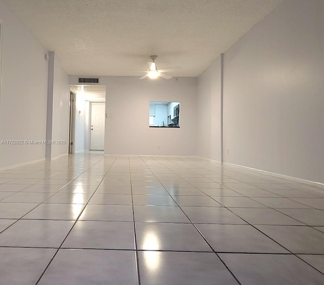 empty room featuring light tile patterned floors, a textured ceiling, and ceiling fan