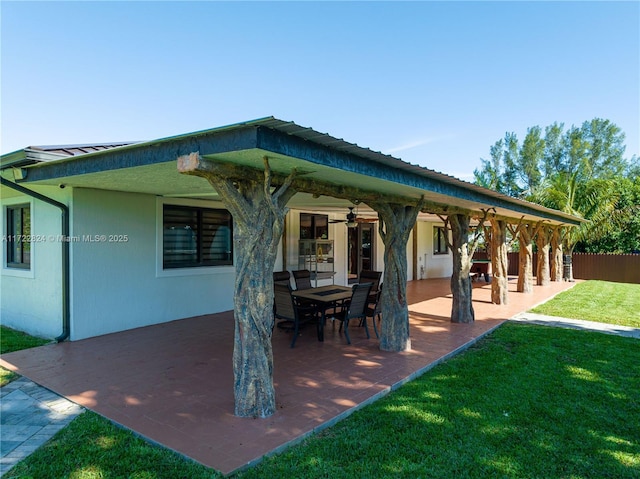 back of property featuring ceiling fan, a patio area, and a lawn