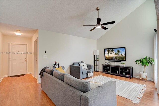 living room with ceiling fan, lofted ceiling, a textured ceiling, and light hardwood / wood-style floors