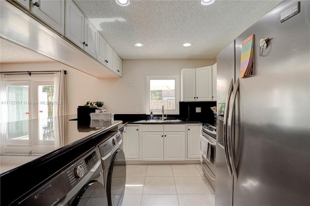 kitchen with stainless steel appliances, a sink, white cabinetry, independent washer and dryer, and dark countertops