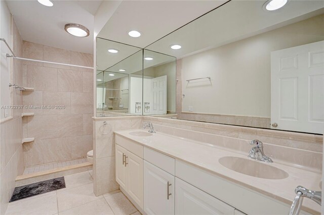 bathroom with vanity, tile patterned floors, toilet, and a tile shower