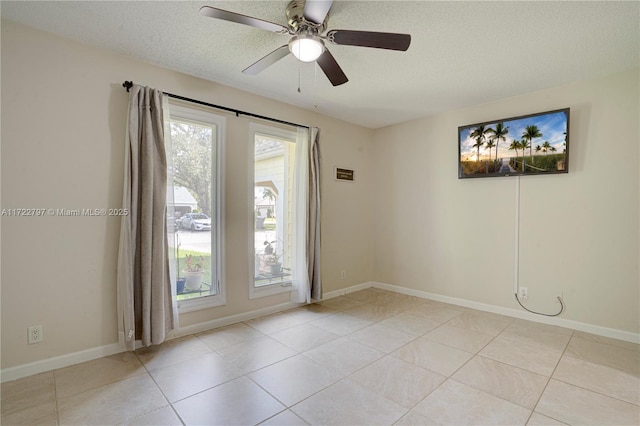 spare room with a textured ceiling, ceiling fan, light tile patterned floors, and baseboards