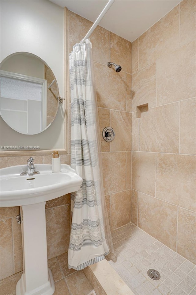 bathroom with a stall shower and tile walls