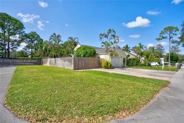 exterior space featuring a garage, concrete driveway, and a fenced front yard