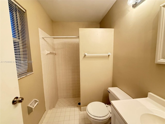 bathroom featuring a tile shower, tile patterned floors, vanity, and toilet