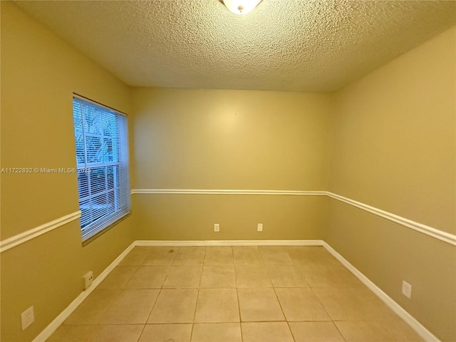 unfurnished room with tile patterned flooring and a textured ceiling