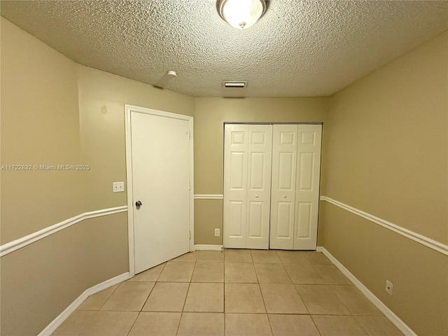 unfurnished bedroom with light tile patterned floors, a textured ceiling, and a closet