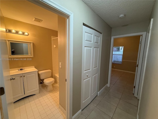 bathroom with tile patterned flooring, a textured ceiling, vanity, and toilet