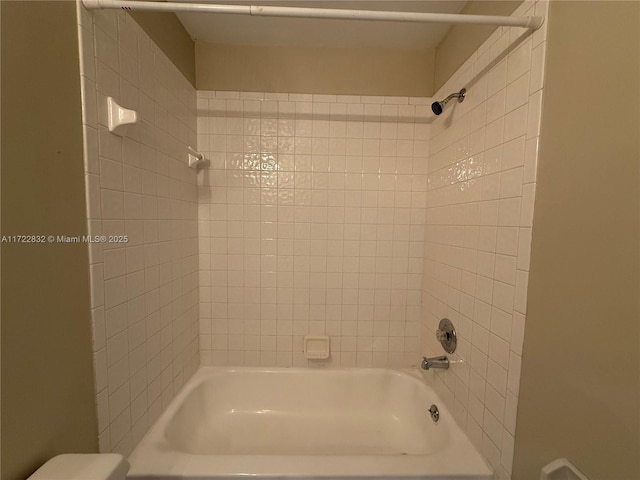 bathroom featuring toilet and tiled shower / bath