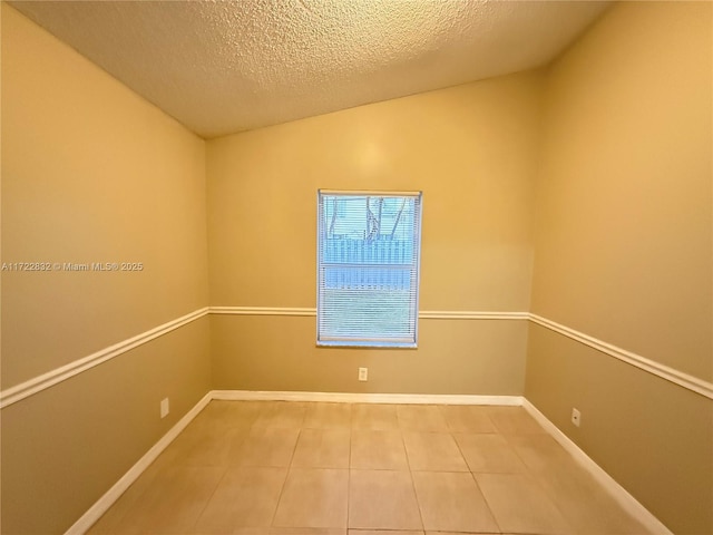 tiled empty room featuring a textured ceiling