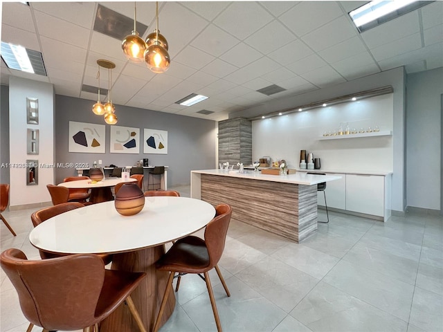 dining area with bar area and a drop ceiling