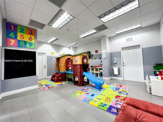 game room with a paneled ceiling and tile patterned floors