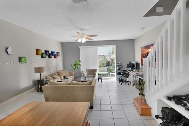 living room featuring ceiling fan, light tile patterned floors, and a textured ceiling