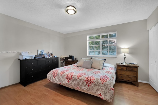 bedroom with a closet, light hardwood / wood-style flooring, and a textured ceiling