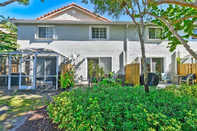 back of property featuring glass enclosure and a patio