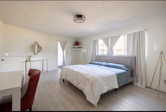 bedroom featuring a textured ceiling and light hardwood / wood-style flooring