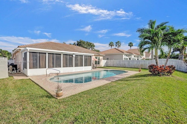 back of house featuring a sunroom, a fenced in pool, a patio, and a lawn