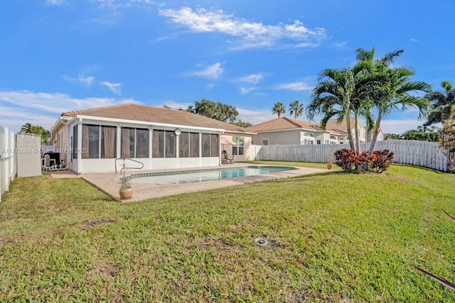 back of property with a sunroom, a patio area, a fenced in pool, and a yard