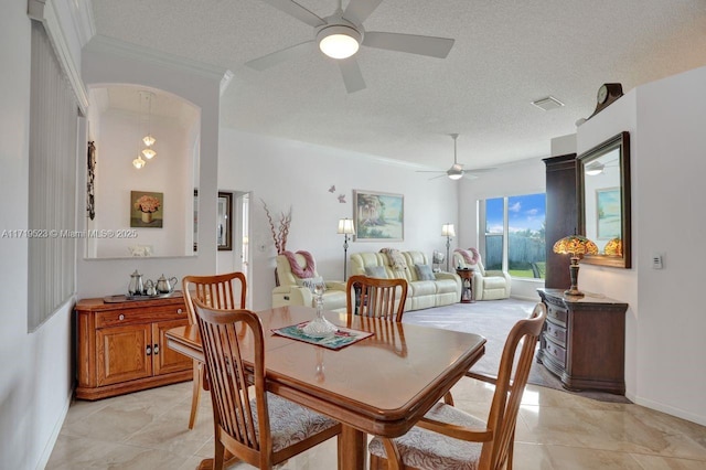 tiled dining area featuring a textured ceiling, ceiling fan, and crown molding