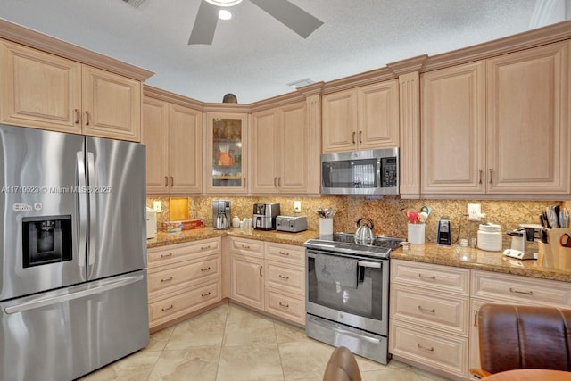 kitchen featuring light stone countertops, light brown cabinets, stainless steel appliances, tasteful backsplash, and a textured ceiling