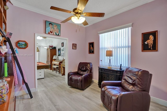 living area with ceiling fan, crown molding, light hardwood / wood-style floors, and a textured ceiling