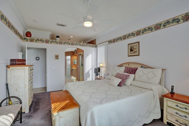 carpeted bedroom with ceiling fan, ornamental molding, and ensuite bathroom