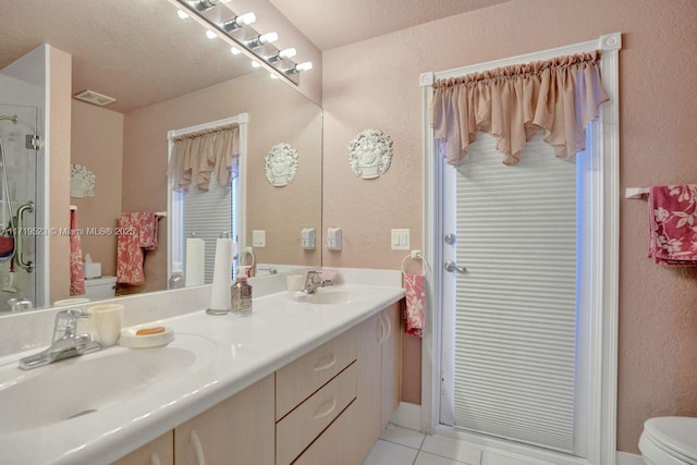 bathroom with tile patterned flooring, vanity, toilet, and a textured ceiling