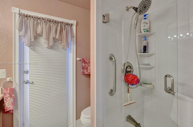 bathroom featuring toilet and a shower with door