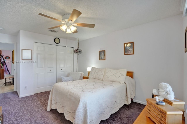 bedroom featuring ceiling fan, a closet, a textured ceiling, and dark colored carpet