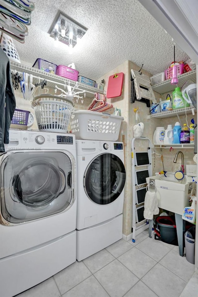 clothes washing area with a textured ceiling, washing machine and dryer, and light tile patterned flooring