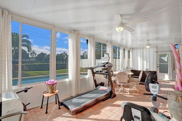 exercise area featuring ceiling fan and a water view