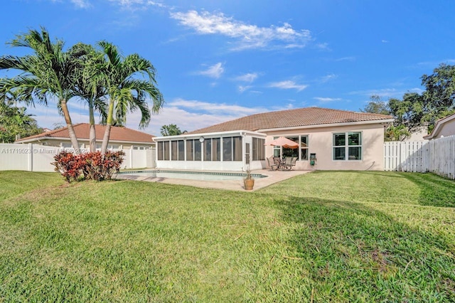 back of property featuring a yard, a patio, a fenced in pool, and a sunroom