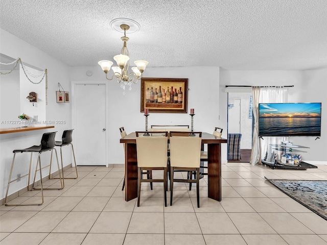 tiled dining space with a notable chandelier and a textured ceiling