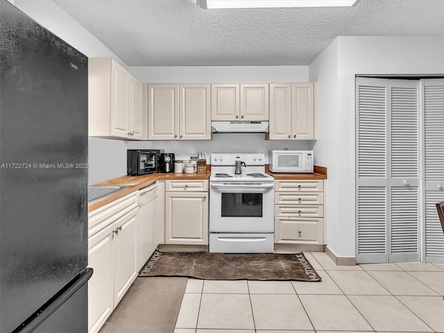 kitchen featuring butcher block counters, white appliances, a textured ceiling, and light tile patterned floors