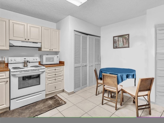 kitchen with a textured ceiling, light tile patterned floors, and white appliances