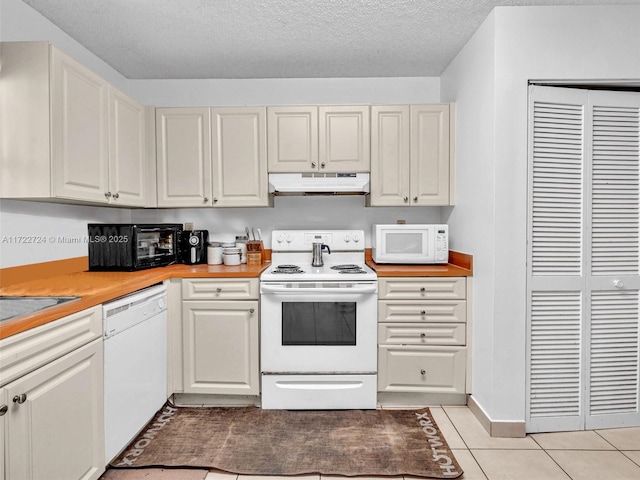 kitchen with light tile patterned flooring, white appliances, and a textured ceiling