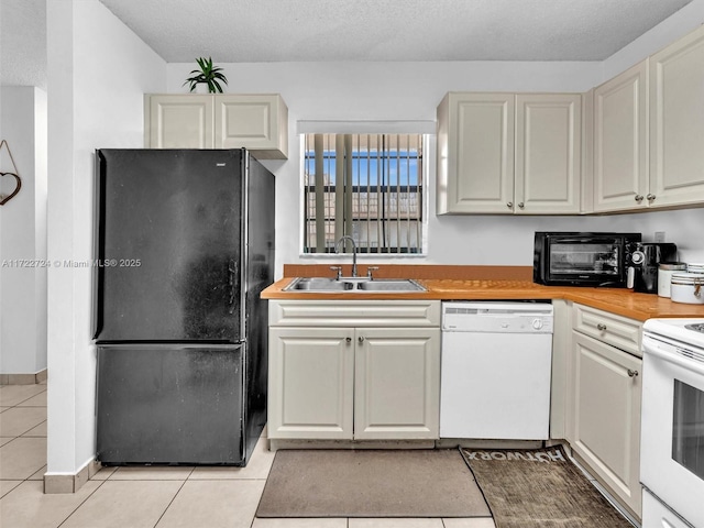 kitchen featuring a textured ceiling, sink, light tile patterned floors, and white appliances