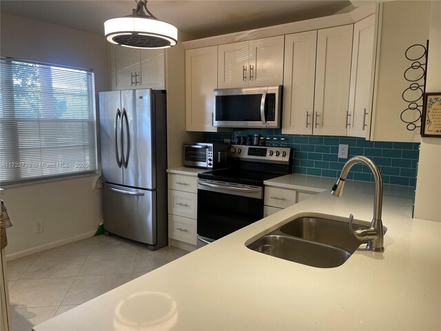 kitchen with tasteful backsplash, appliances with stainless steel finishes, sink, and white cabinets