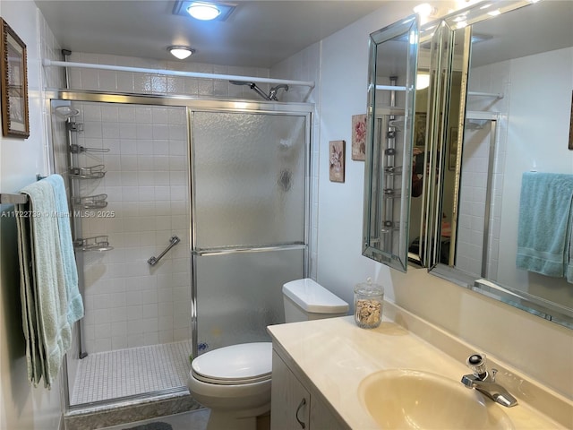 bathroom featuring a shower with door, vanity, and toilet