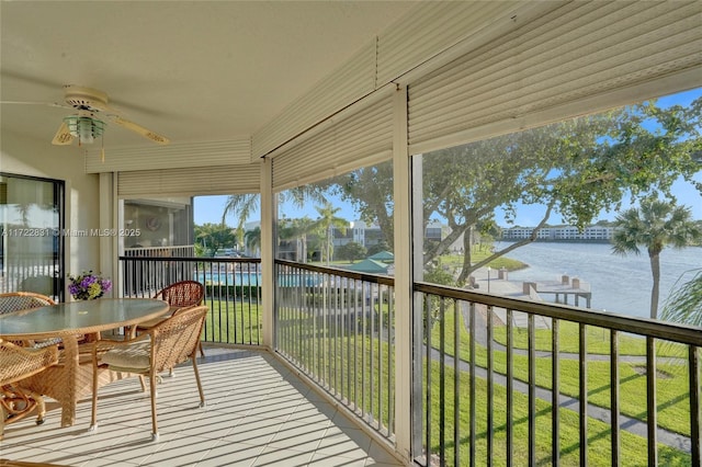 sunroom with ceiling fan and a water view