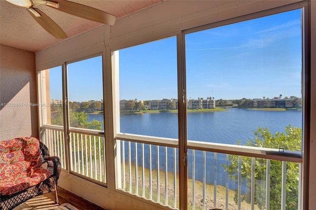 unfurnished sunroom with ceiling fan and a water view