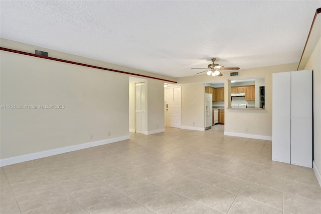 unfurnished living room featuring ceiling fan, light tile patterned flooring, and a textured ceiling