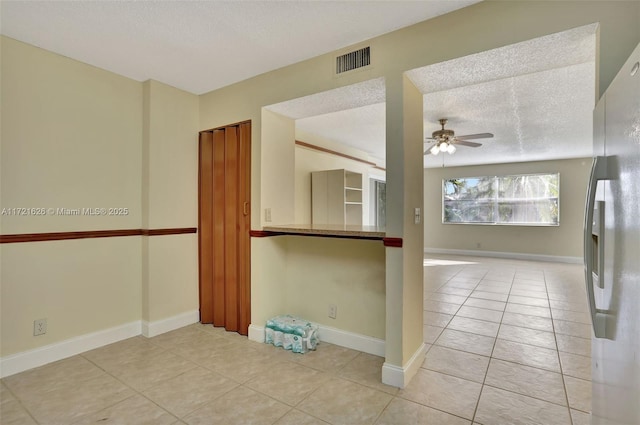 tiled spare room with a textured ceiling and ceiling fan